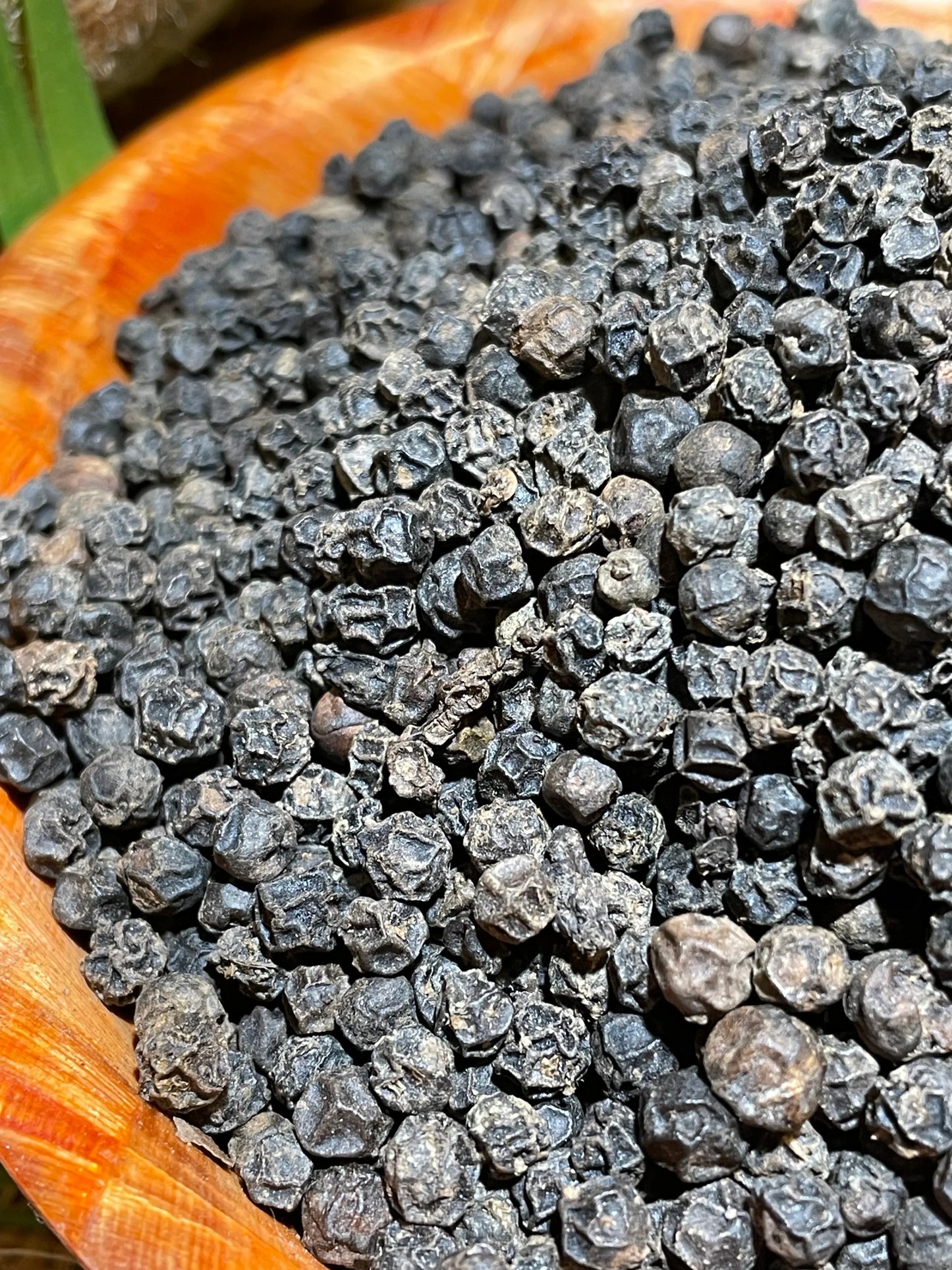 Gros plan sur les grains de poivre fumé de Madagascar, épice artisanale aux arômes boisés