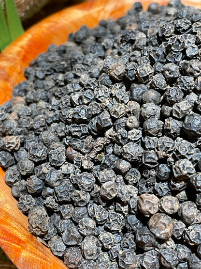 Gros plan sur les grains de poivre fumé de Madagascar, épice artisanale aux arômes boisés