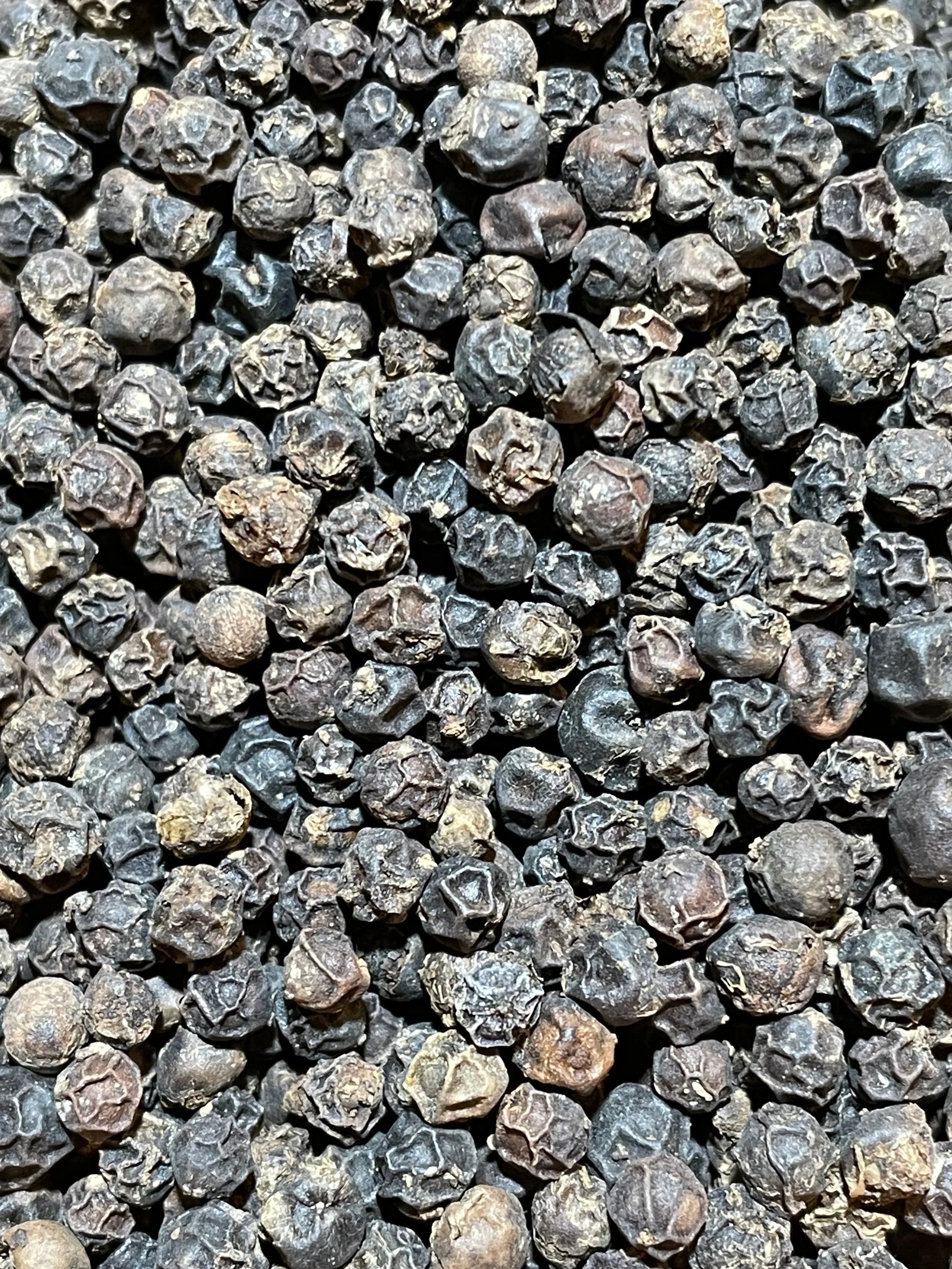 Gros plan sur les grains de poivre Penja Noir, notes boisées, florales et terreuses