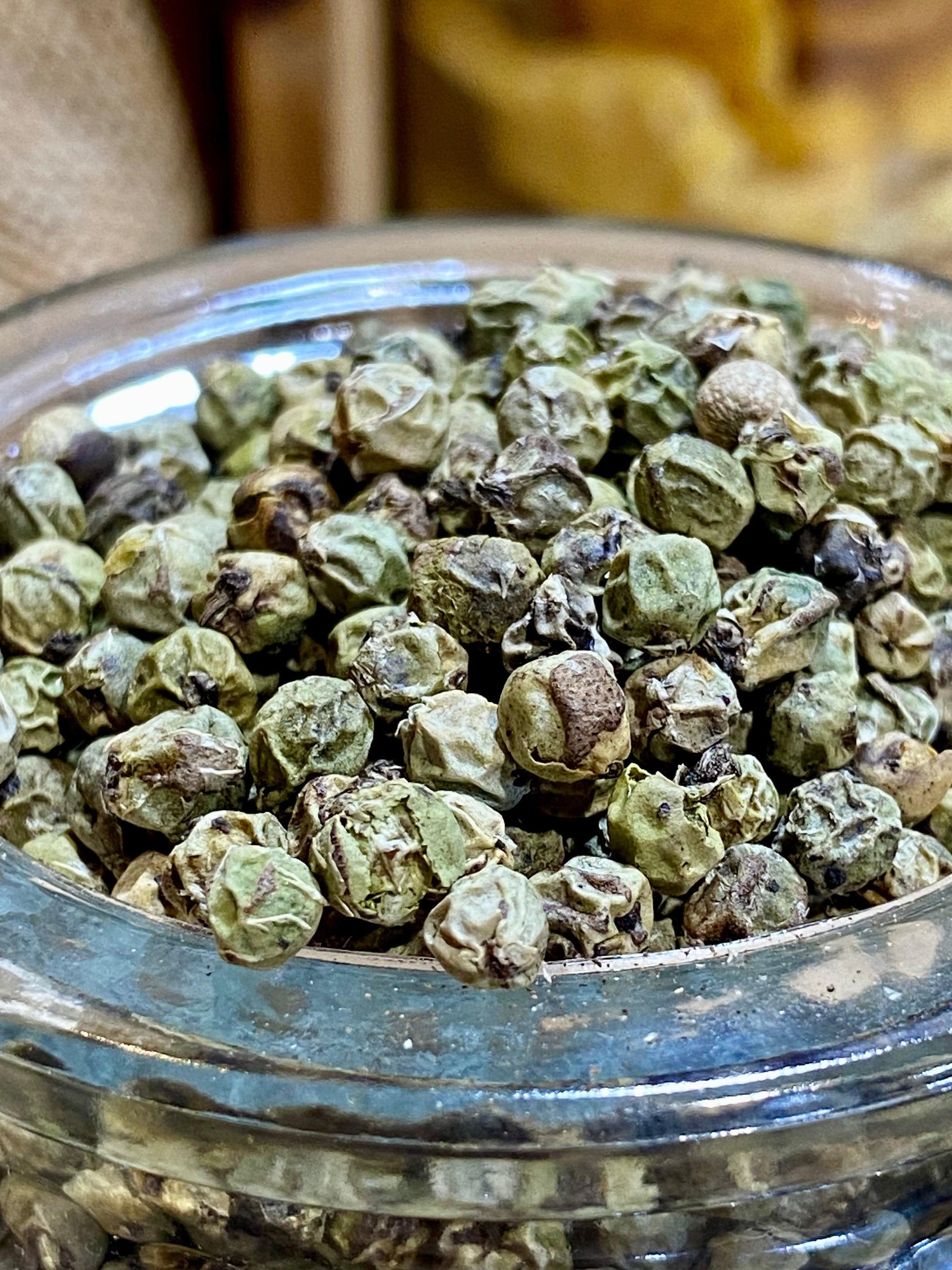 Poivre vert déshydraté en grains présenté dans un bol