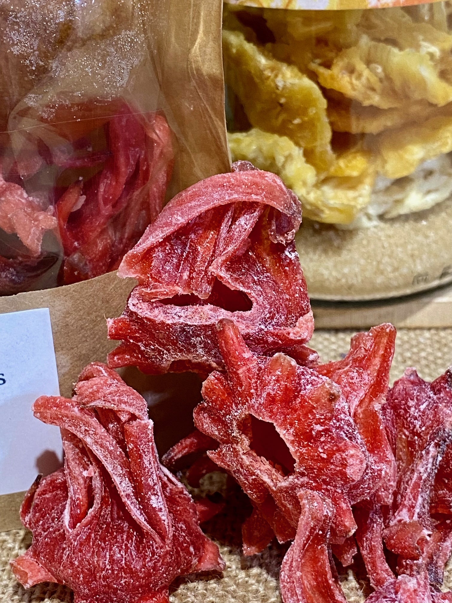 Gros plan sur les ingrédients du rhum arrangé Clémentine Hibiscus – morceaux de clémentine séchée, fleurs d’hibiscus, fève de tonka et baies de Timut pour infusion aromatique dans le rhum