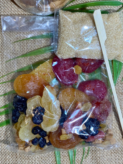 Gros plan sur les ingrédients du rhum arrangé La Breizhitude – pommes séchées, cerises confites, myrtilles, raisins, fraises, abricot au jus de coquelicot, piment d’Espelette et caramel au beurre salé prêts à infuser dans du rhum blanc agricol